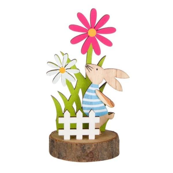 Figurina decor pentru masa de Paste, iepuras pe stativ din lemn, gard alb, iarba verde si flori multicolor de primavara, inaltime 13.5 cm