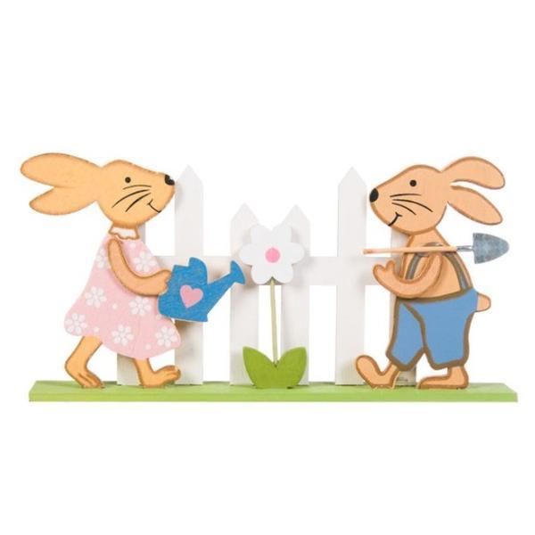 Figurina decor pentru masa de paste, doi iepurasi din lemn care ingrijesc o floare din gradina imprejmuita cu gard, lungime 22.5 cm