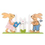 Figurina decor pentru masa de Paste, doi iepurasi din lemn care ingrijesc o floare din gradina imprejmuita cu gard, lungime 22.5 cm